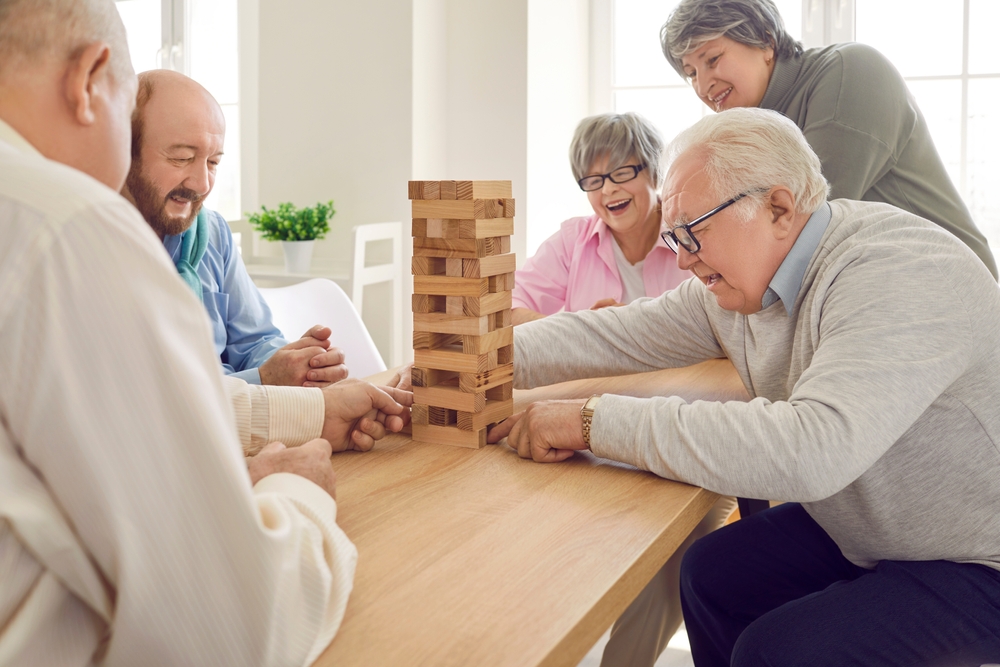Group of happy senior people having fun and playing board games in community centre